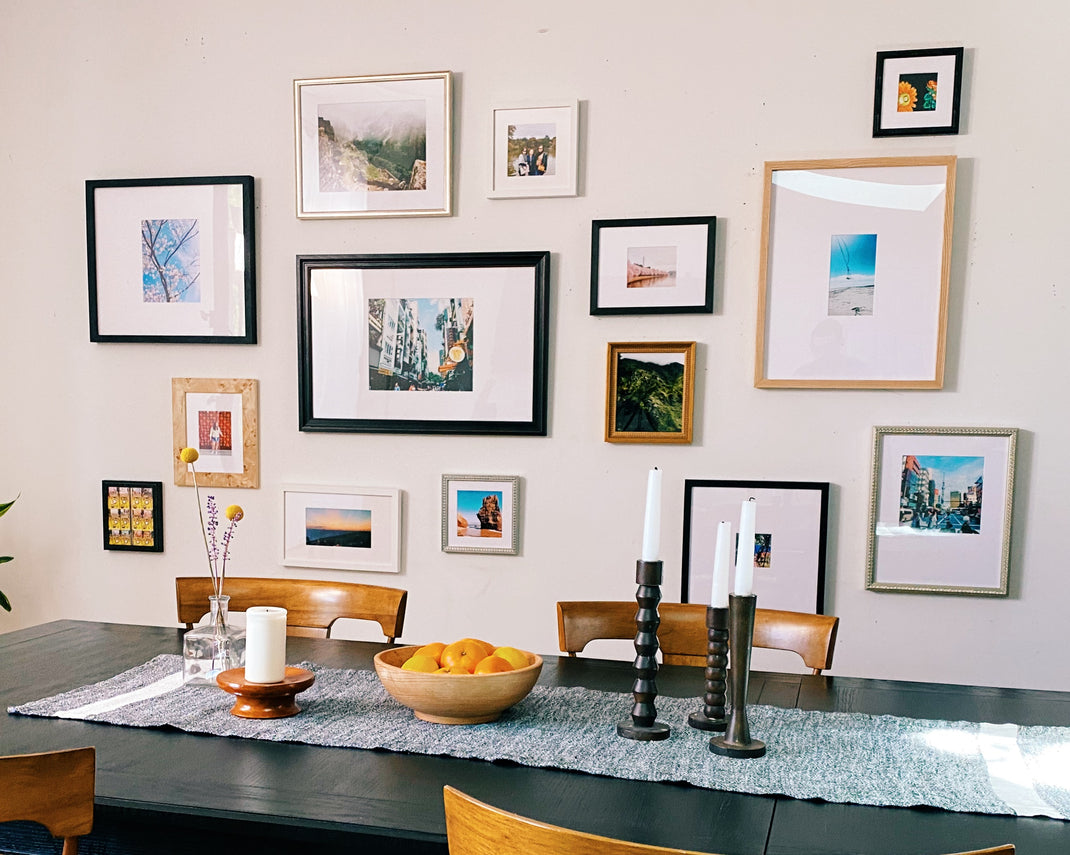 airy imperfect gallery wall with cool tone frames hanging over a dining room table