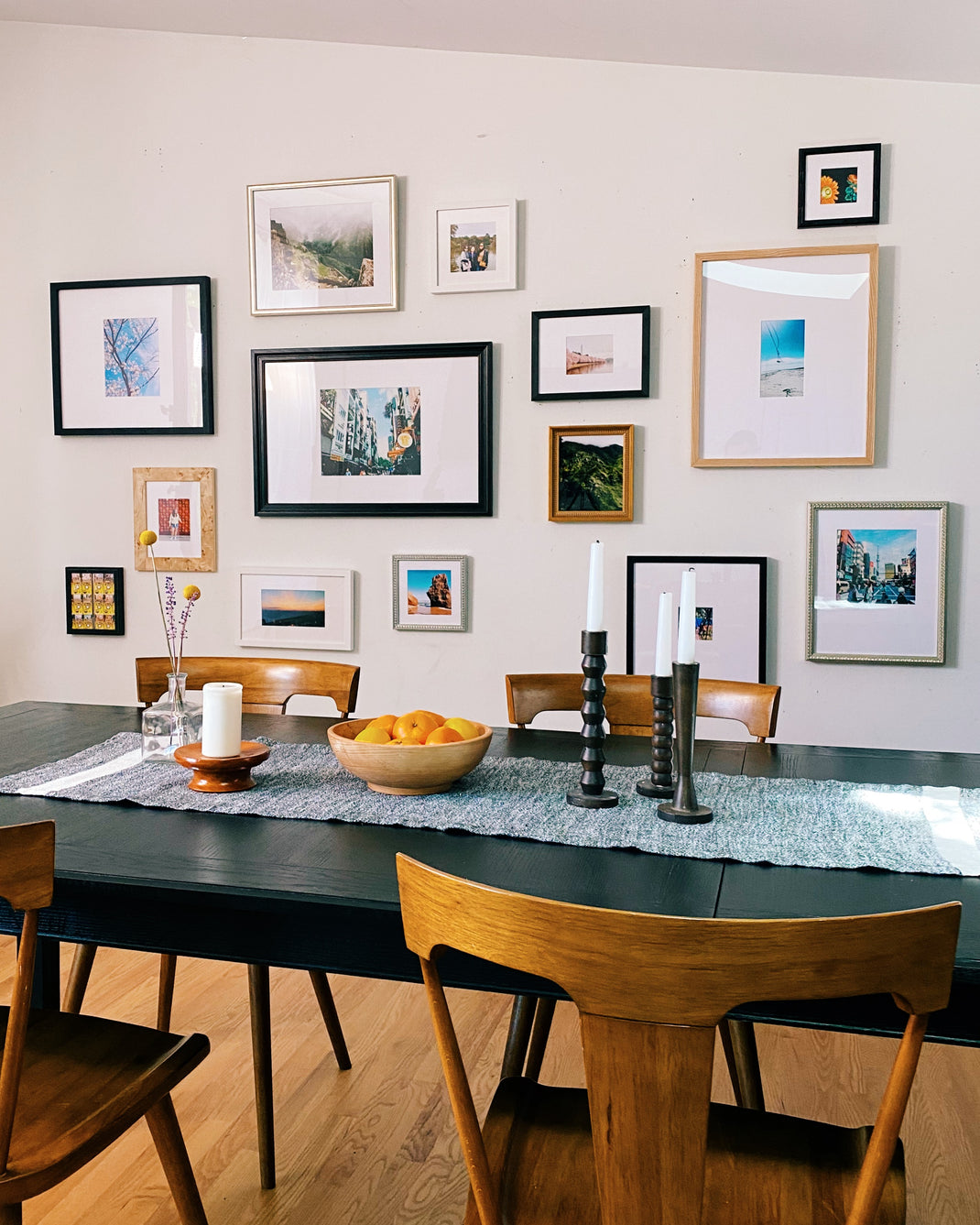cool airy imperfect gallery wall with cool tone frames hanging over a dining room table