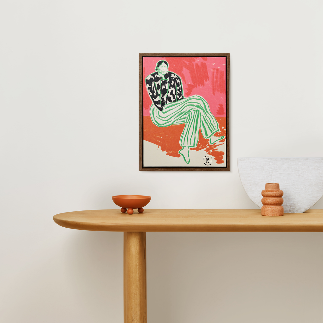 colorful canvas painting of stylish woman in a walnut floater frame hanging on a white wall above wood console table