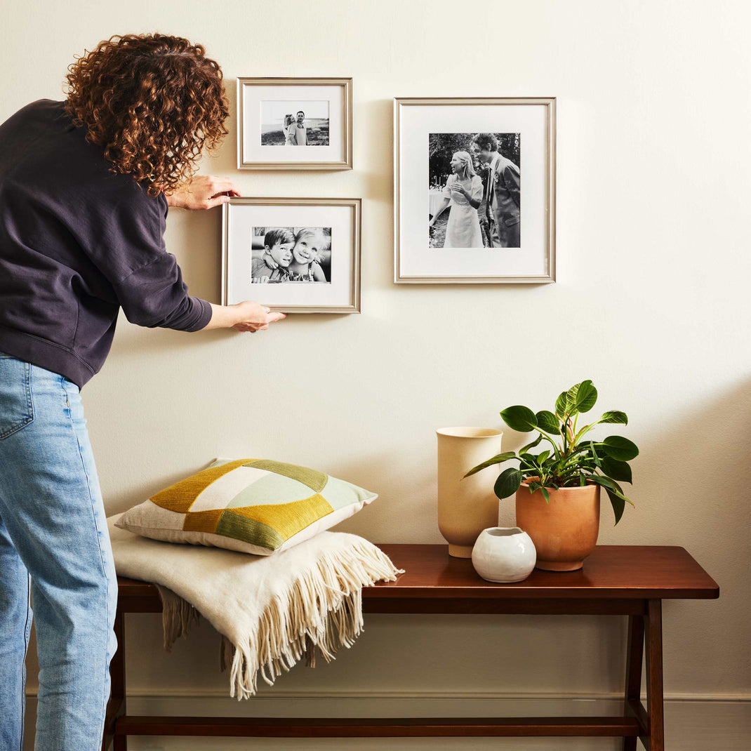 Woman hanging the Timeless Trio Gallery Wall in Newport
