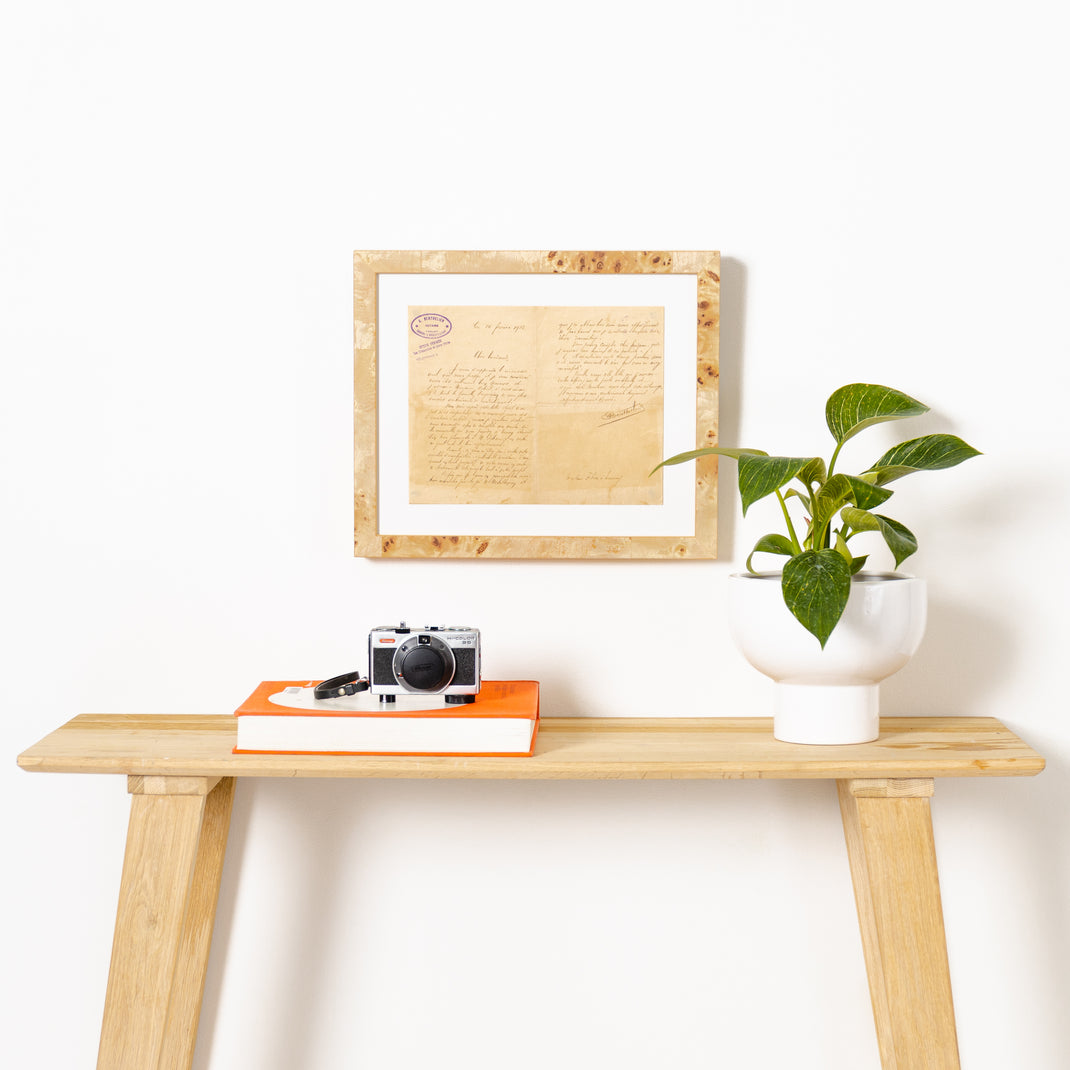 vintage handwritten letter framed in gallery burl wood Giza frame with a white mat hanging on a white wall above a wood console table
