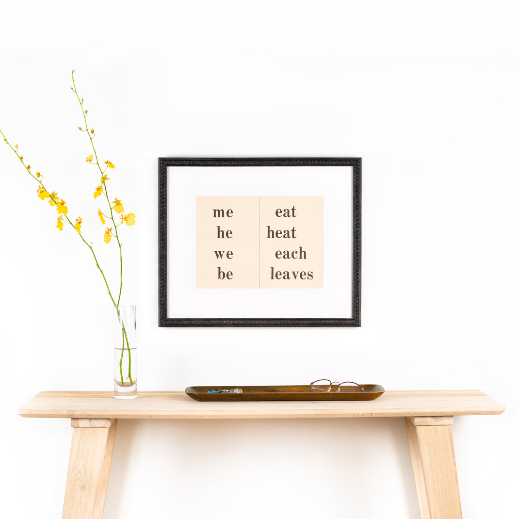 pages of a sight words book framed in wavy matte black Gresham frame with white mat hanging on wall above a wooden console table