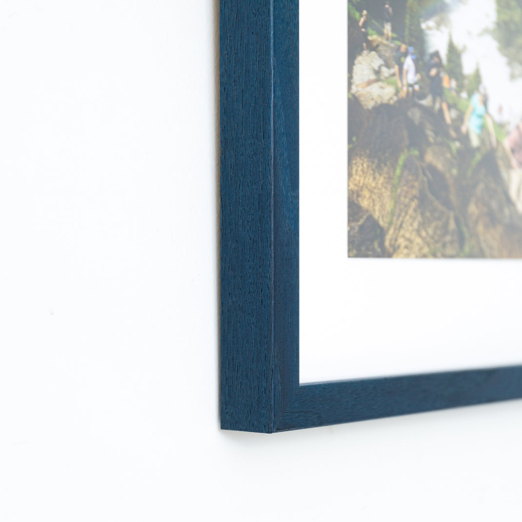 bottom left corner of photograph of hikers framed in Indigo Walnut frame with white mat