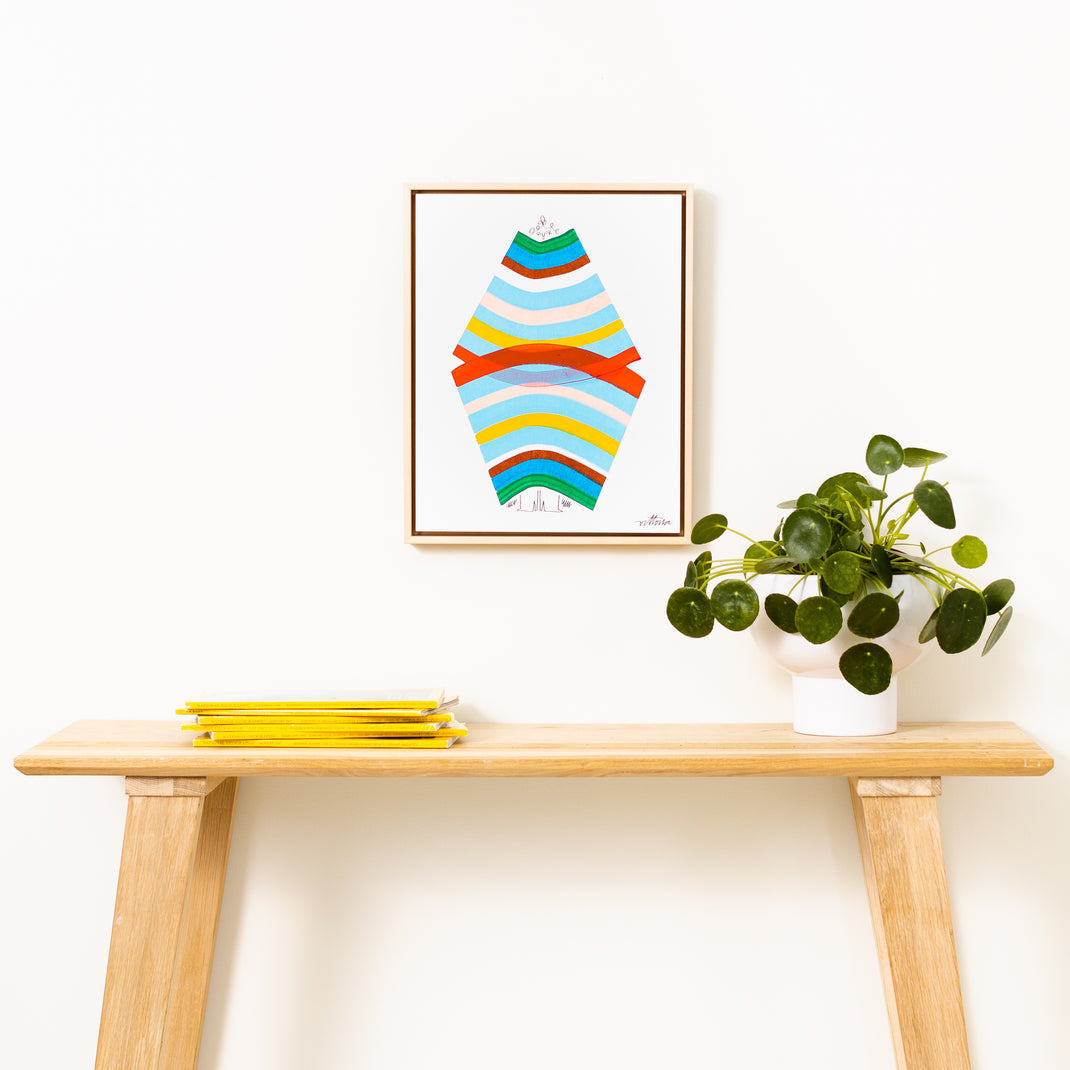 abstract rainbow portrait framed in Laguna natural wood canvas floater frame hanging on a white wall over a wood console table