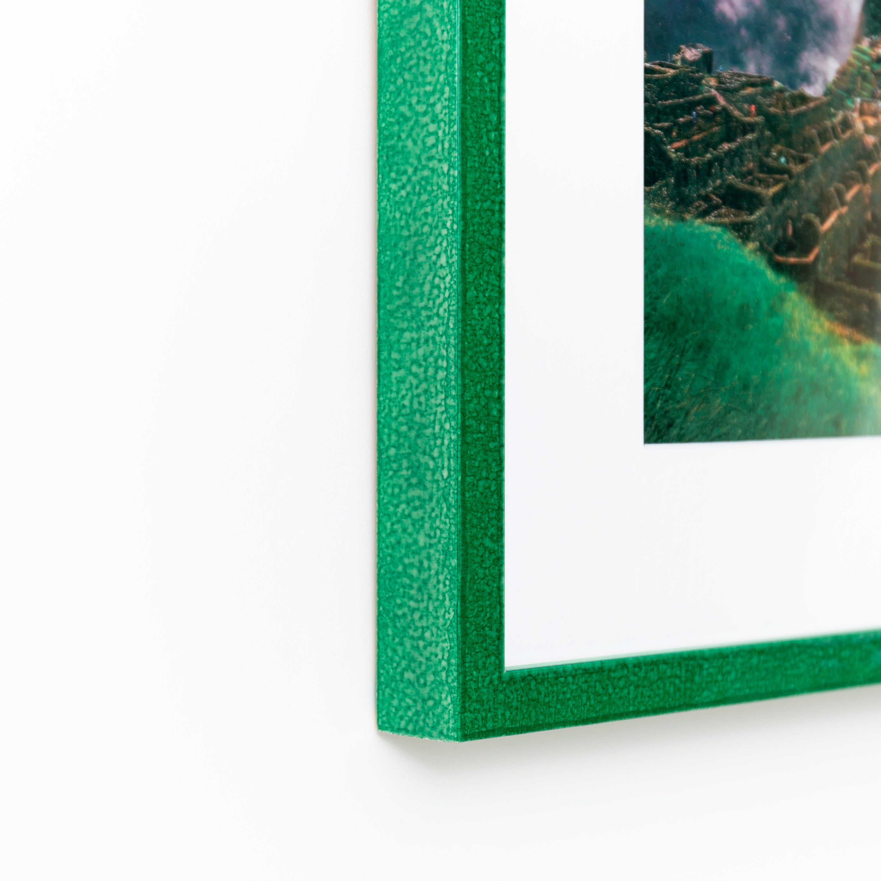 bottom left corner of photograph of Machu Picchu framed in glazed emerald green Lima frame with a white mat