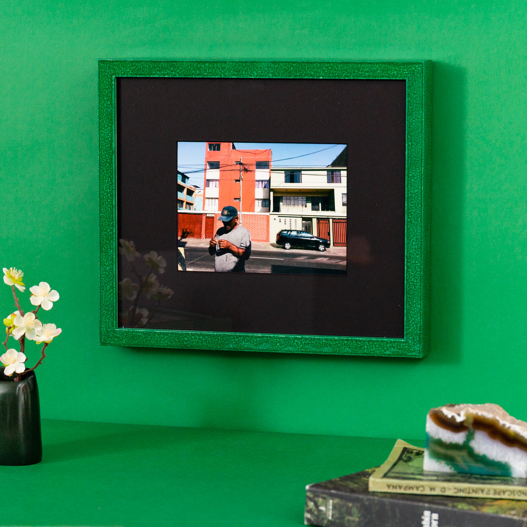 urban photo of a man on a street framed in framed in glazed green Lima frame hanging on a green wall