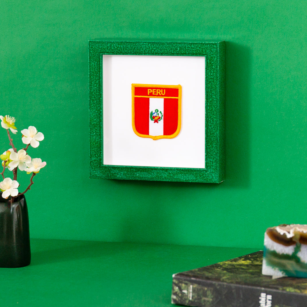 Peru patch framed in glazed green Lima frame hanging on a green wall