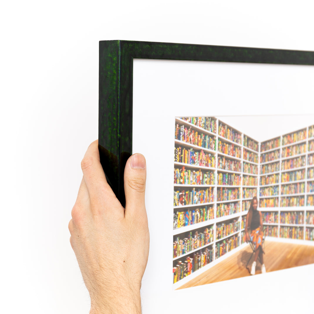 top left corner of photograph of woman in front of books framed in London green glazed frame with a white mat