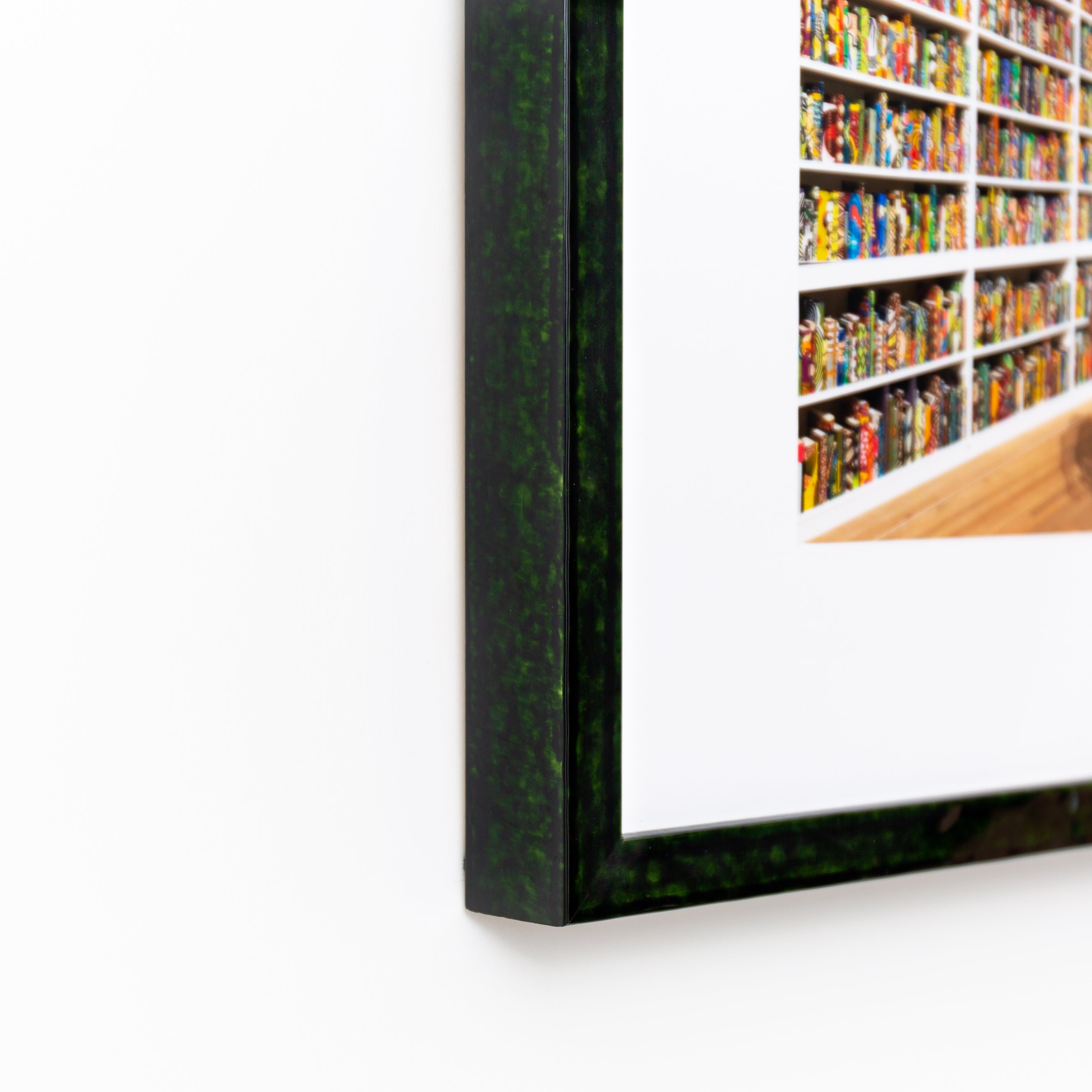 bottom left corner of photograph of woman in front of books framed in London green glazed frame with a white mat