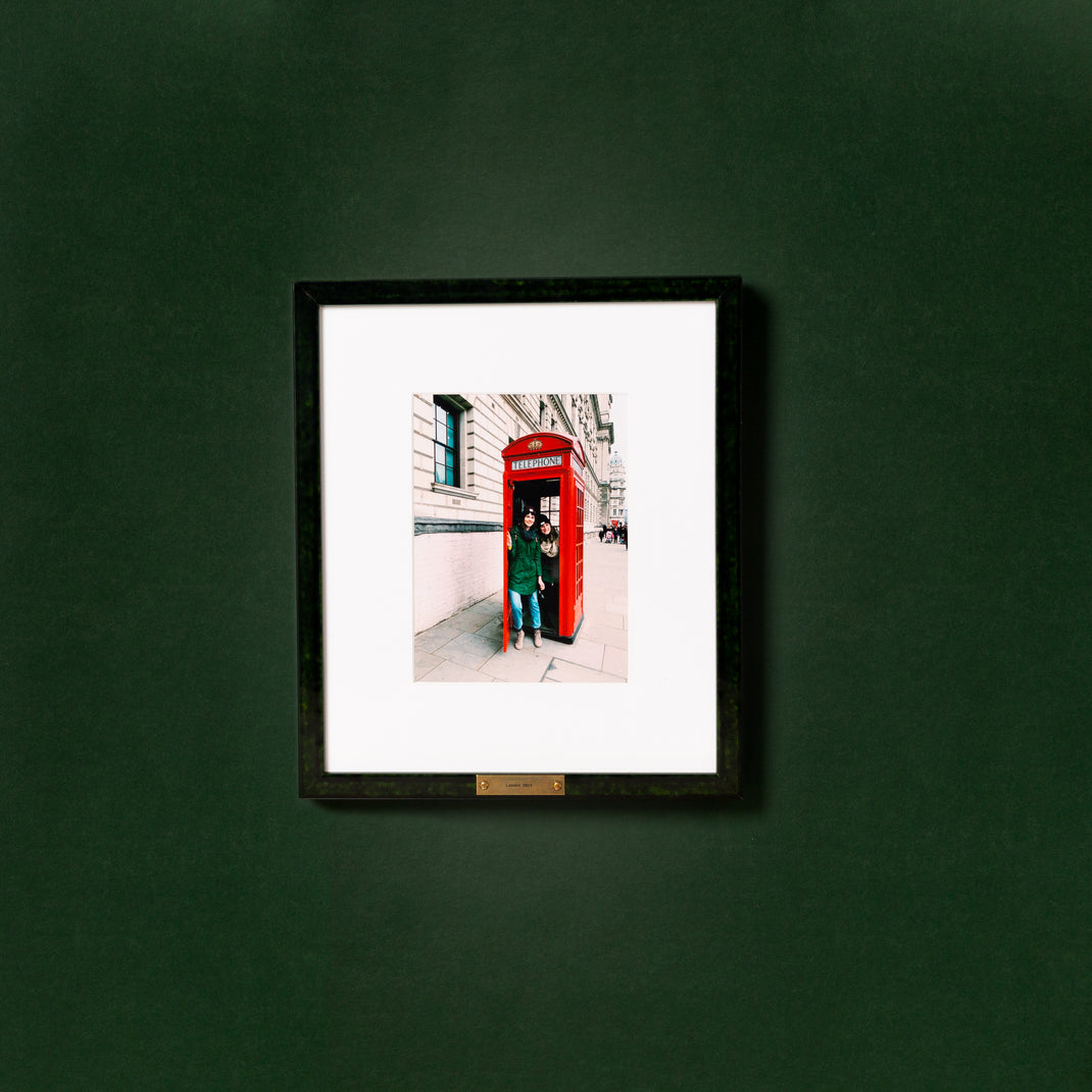 photo of two girls in a London phone booth framed in green glazed London frame with a brass plate