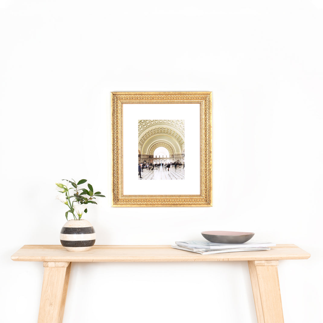 Photo of Union Station in ornate gold Marquette frame with a white mat hanging on a white wall above wood console table