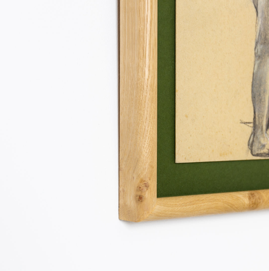 bottom left corner of charcoal figure drawing framed in rounded burl wood frame with a green mat