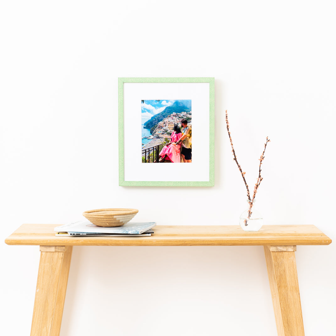 photo of a couple in Italy framed in mint green glazed Positano frame hanging on a white wall above a wood console table