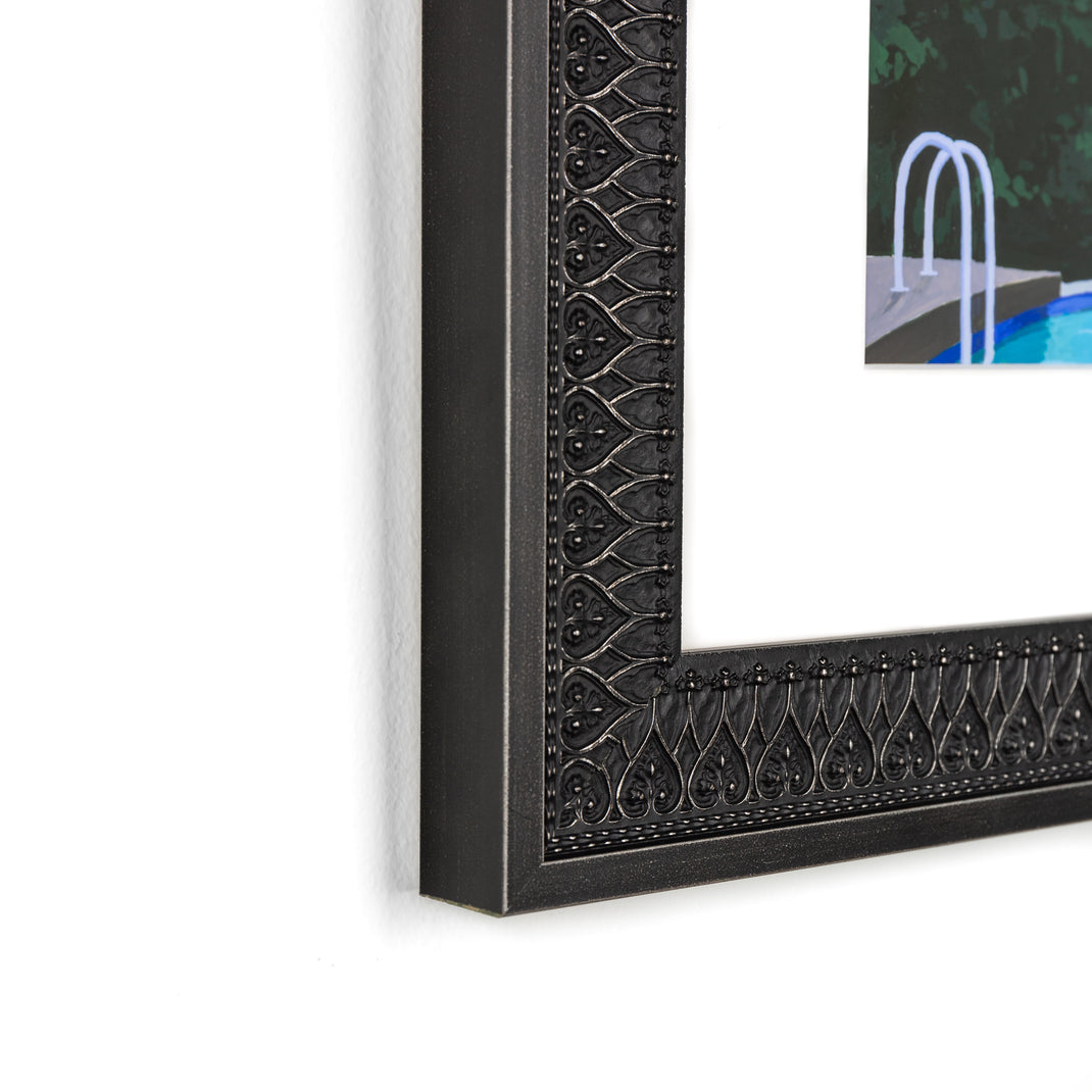 bottom left corner of art print of a man doing a cannonball into a pool framed in ornate black Ravenswood frame with a white mat