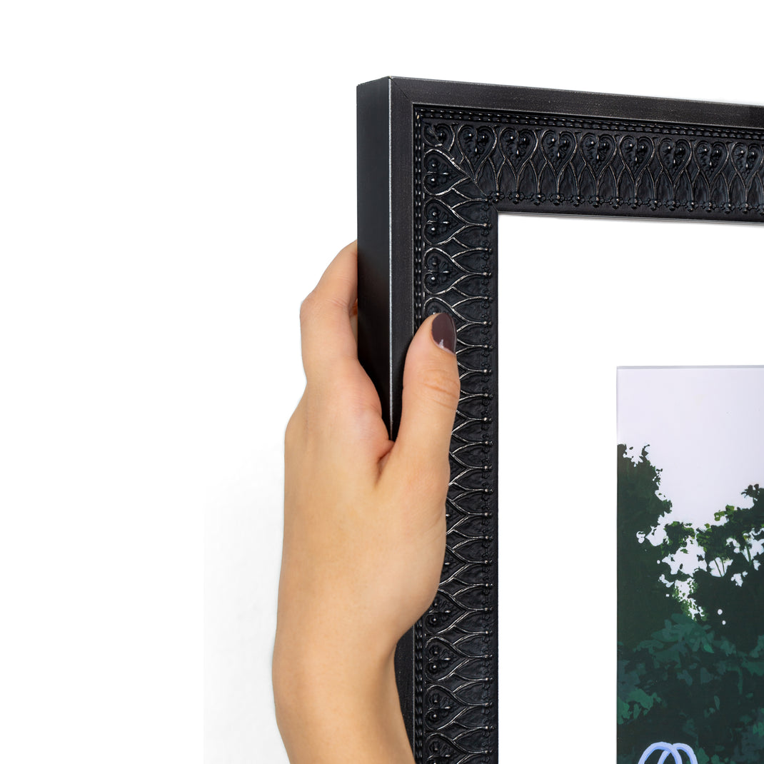 top left corner of art print of a man doing a cannonball into a pool framed in ornate black Ravenswood frame with a white mat