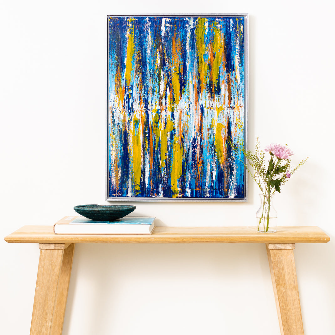 abstract canvas painting in Santiago silver canvas floater style frame hanging on a white wall above a wood console table