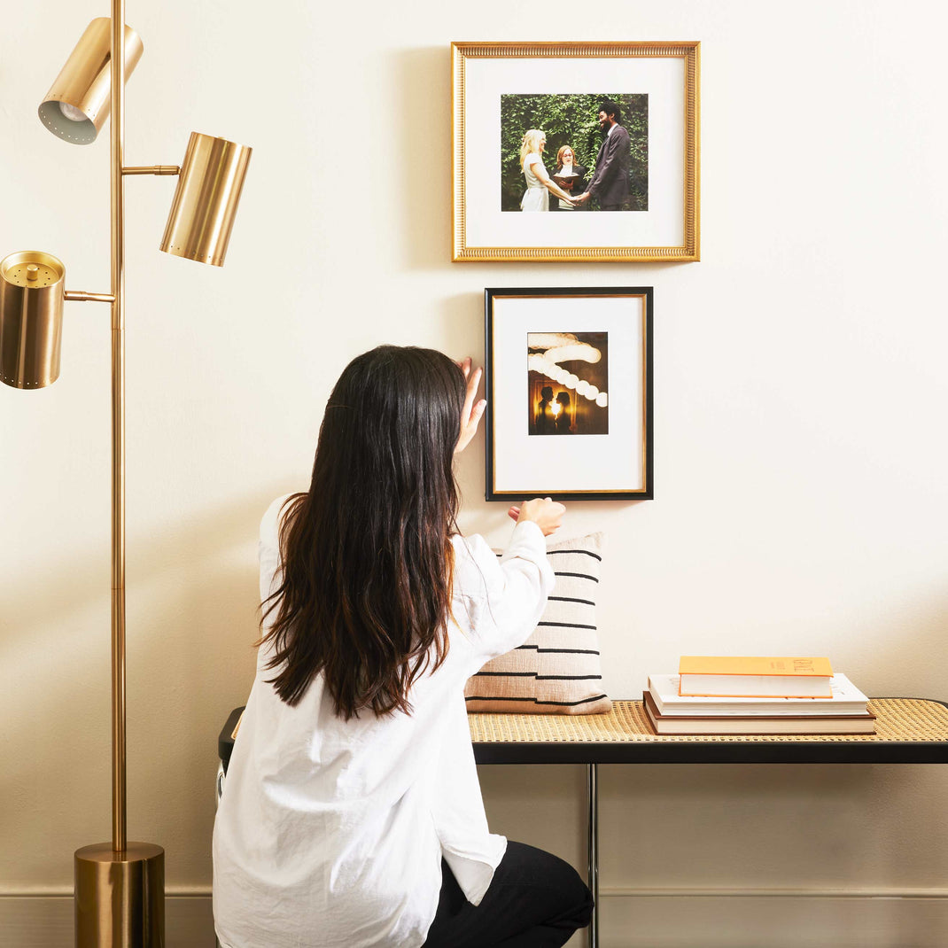 Woman hanging classic two stack gallery wall with gold Georgetown & Providence frames