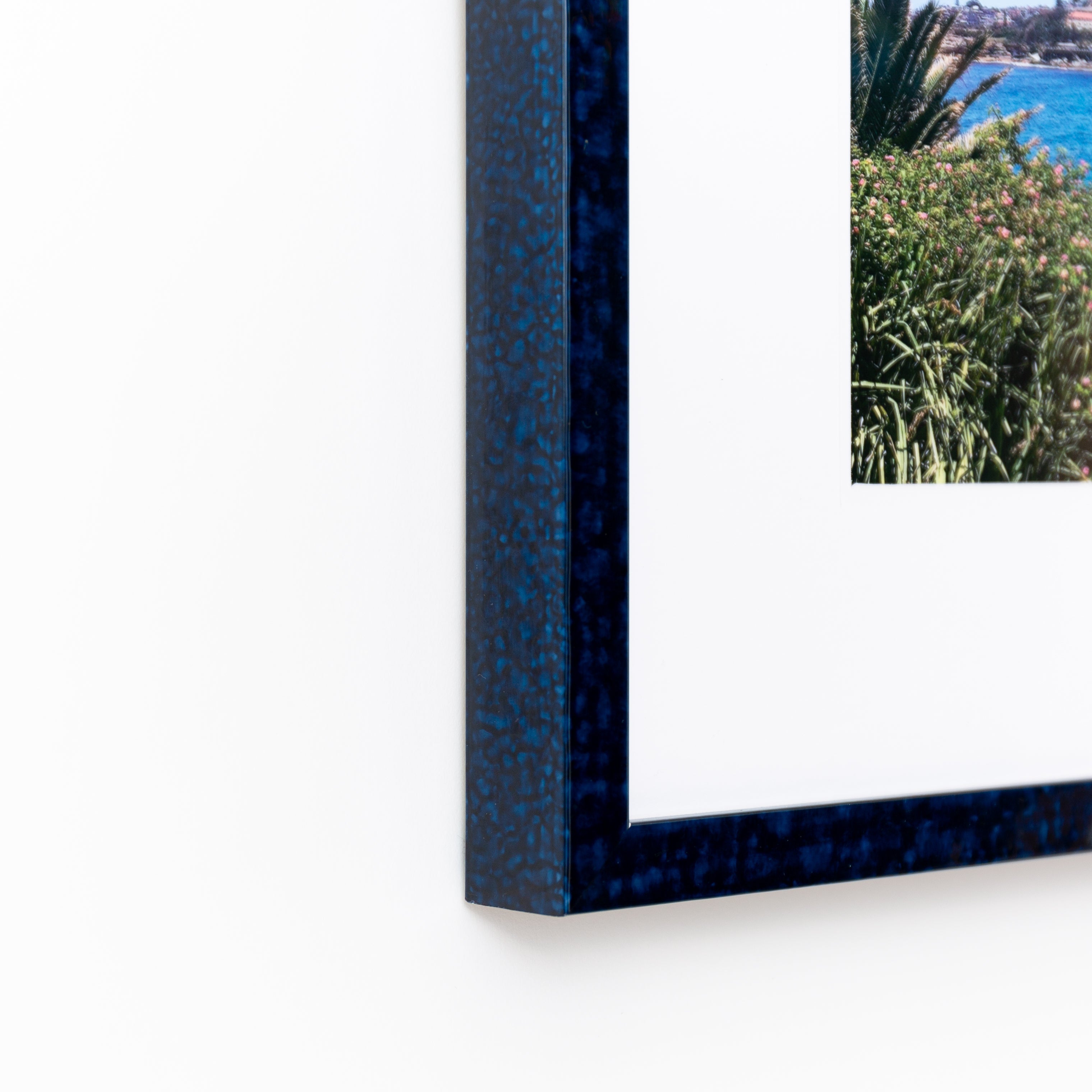 bottom left corner of a landscape photo framed in deep blue glazed Sydney frame with a white mat