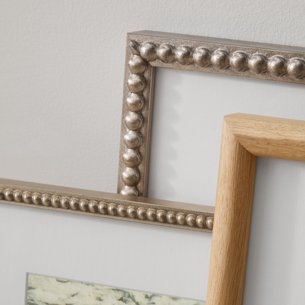 Closeup details of silver beaded and burlwood frames leaning against a wall