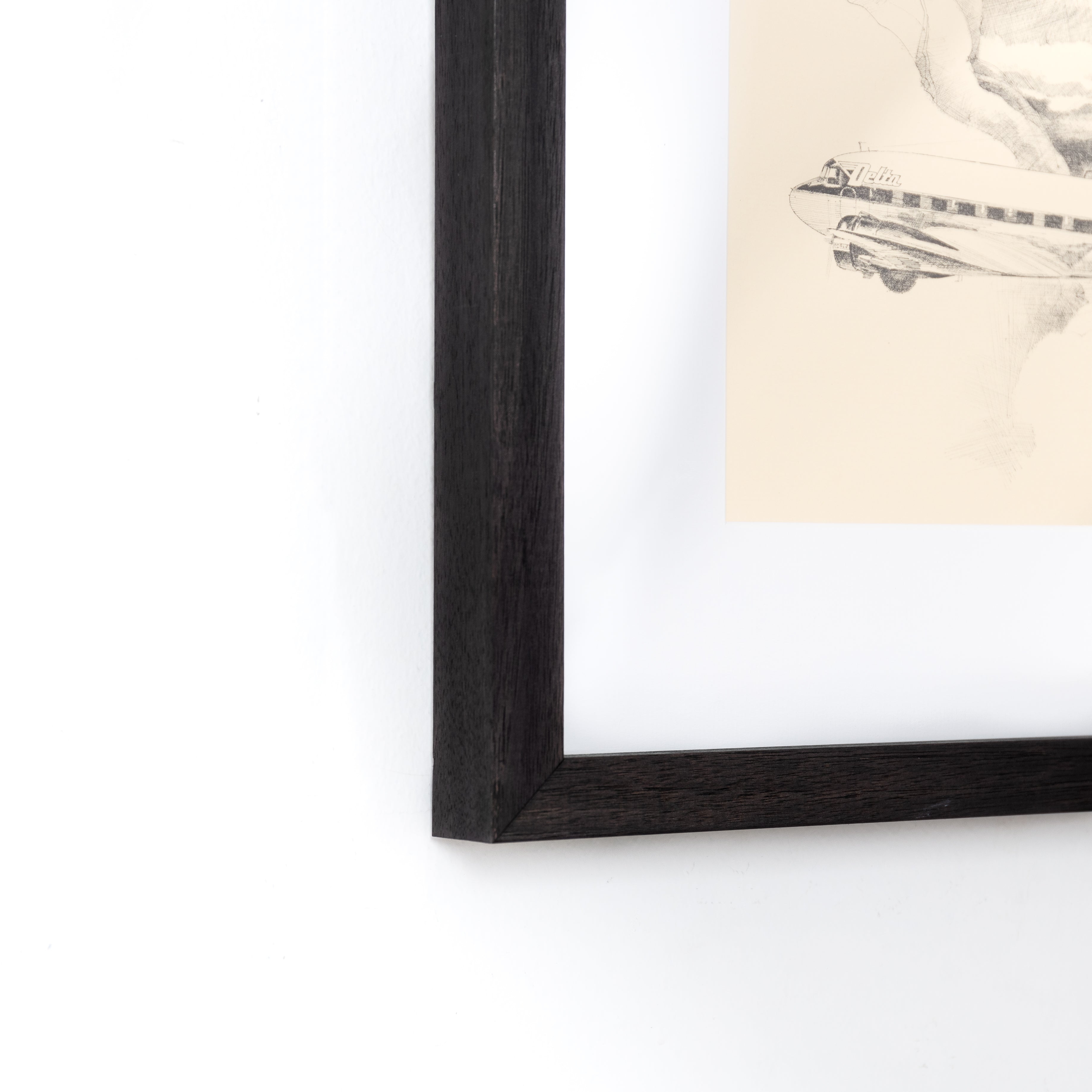 bottom left corner of a Black and white sketch of an airplane framed in Black Walnut Gallery frame with a white mat