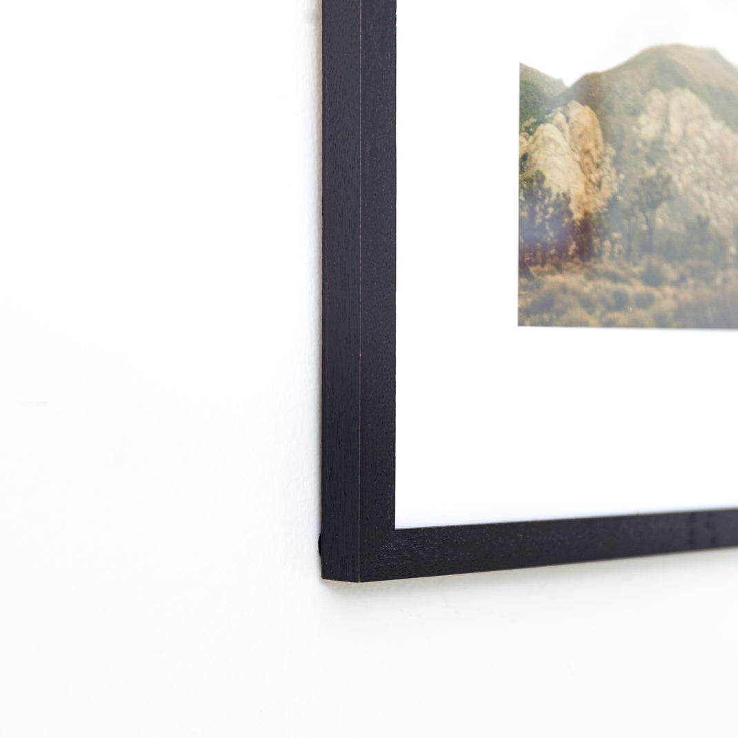 bottom left corner of a Landscape photo of a desert mountain range framed in Black Walnut mini frame with white mat
