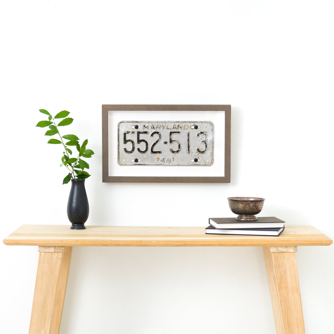 Maryland license plate framed in Gray Ash gallery frame on a white wall above a wood console table
