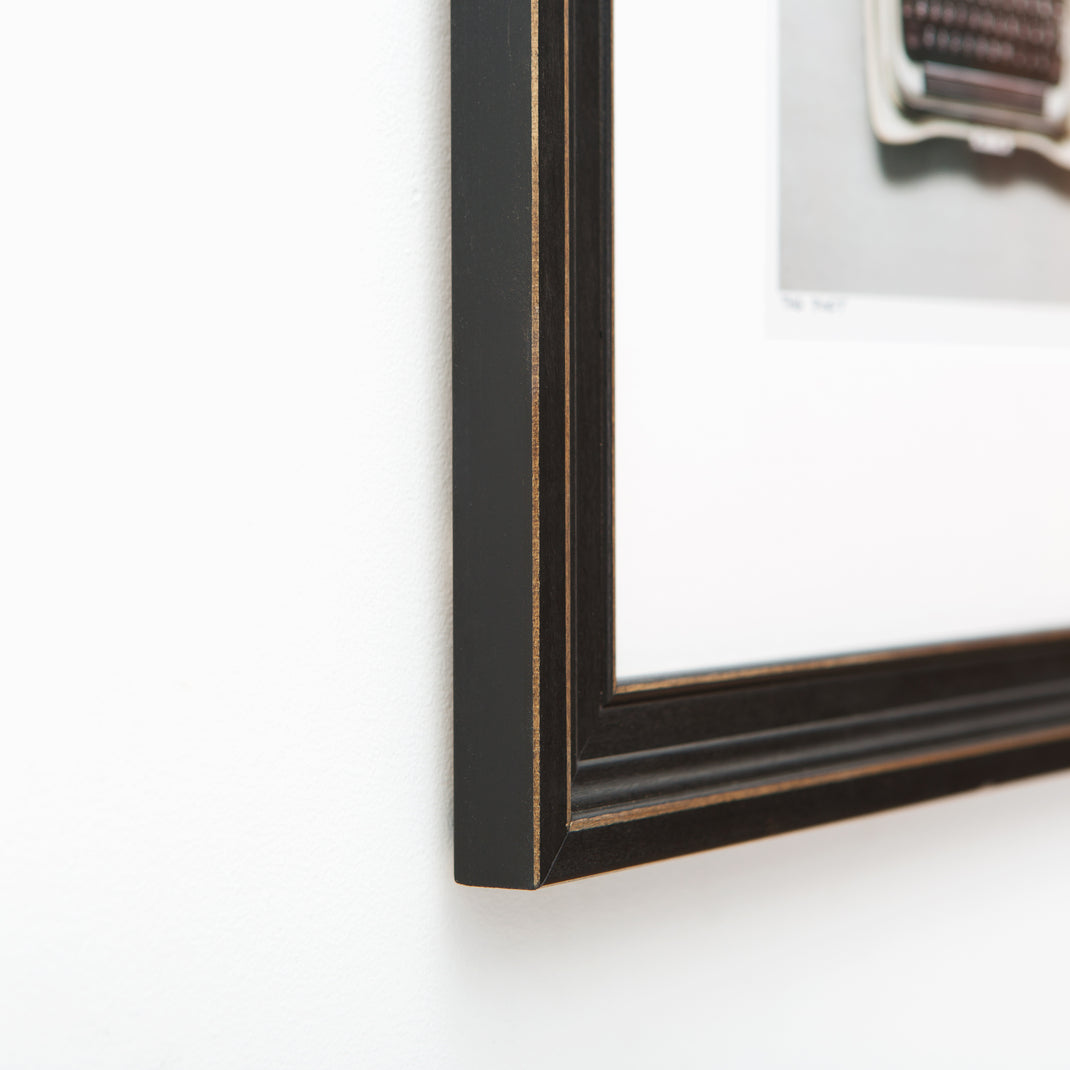 Bottom corner photo of Photo of a typewriter framed in Augusta wide distressed black frame with white mat
