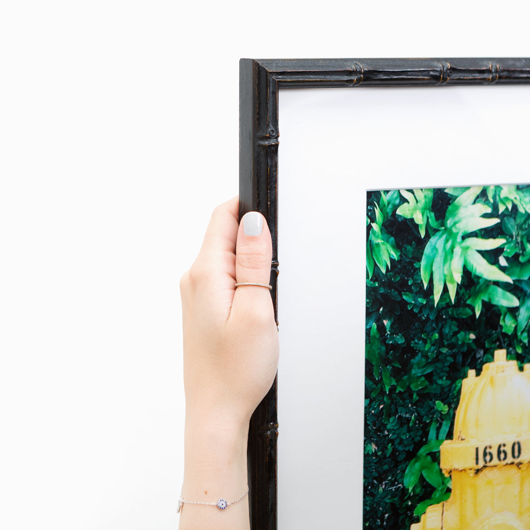 top left corner of Photo of a yellow fire hydrant framed in a black bamboo Bali frame with a white mat
