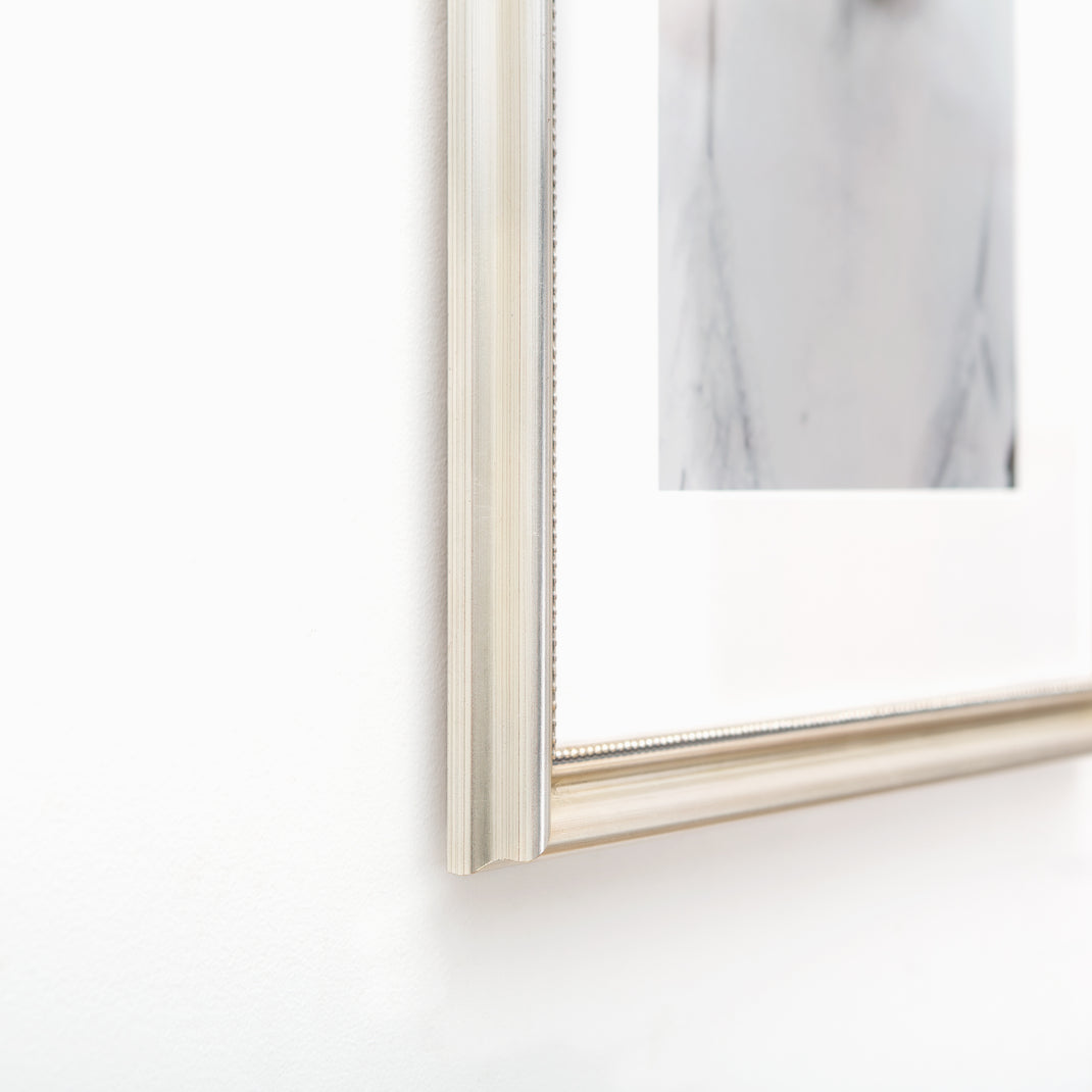 bottom left corner of black and white photo of a woman framed in Buckhead silver beaded frame with white mat