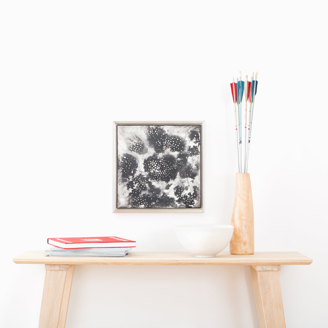 black and white canvas painting framed in Gatwick, a silver floater canvas frame hanging on a white wall above a wood console table