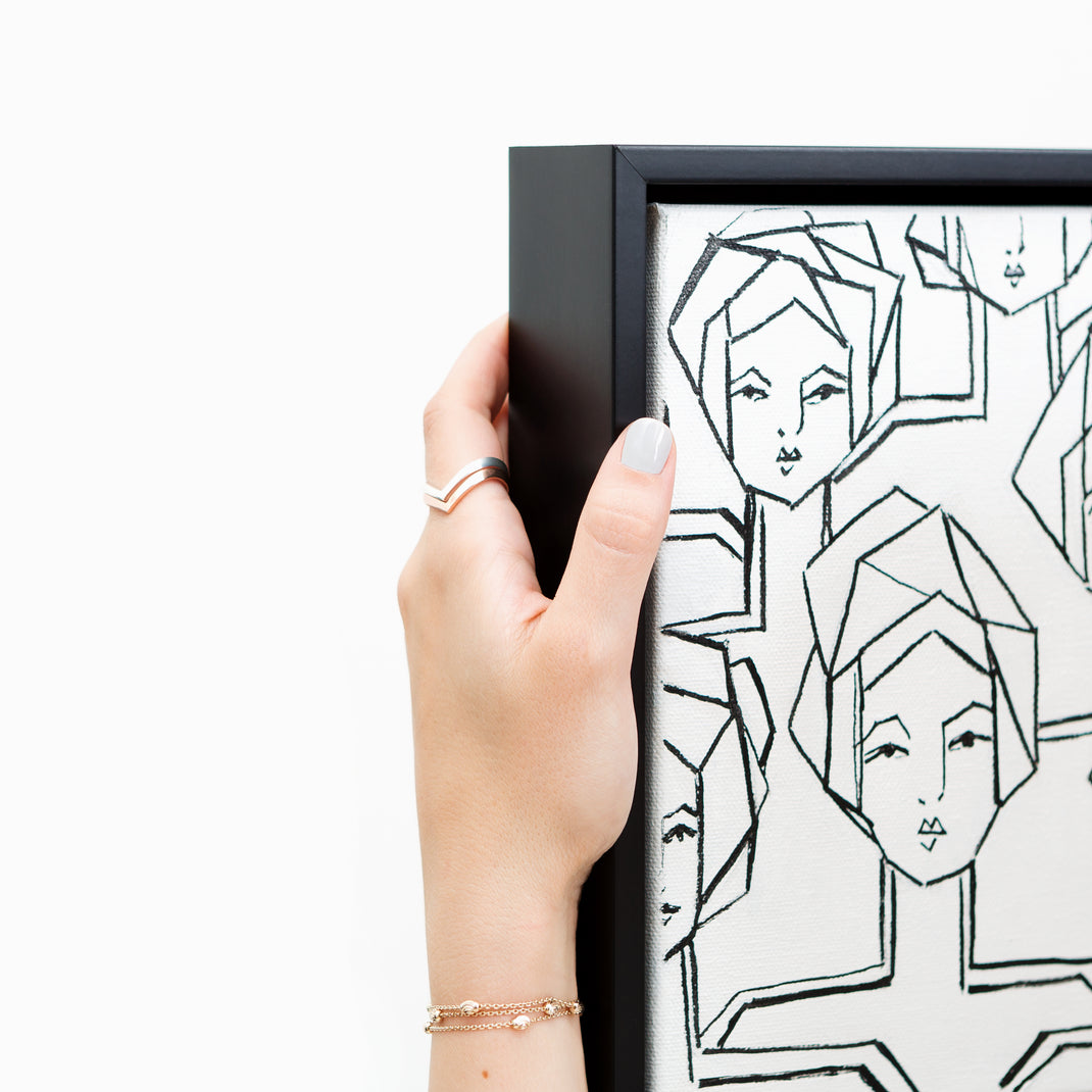 top left corner of black and white line painting of women on canvas framed in Heathrow black canvas floater frame