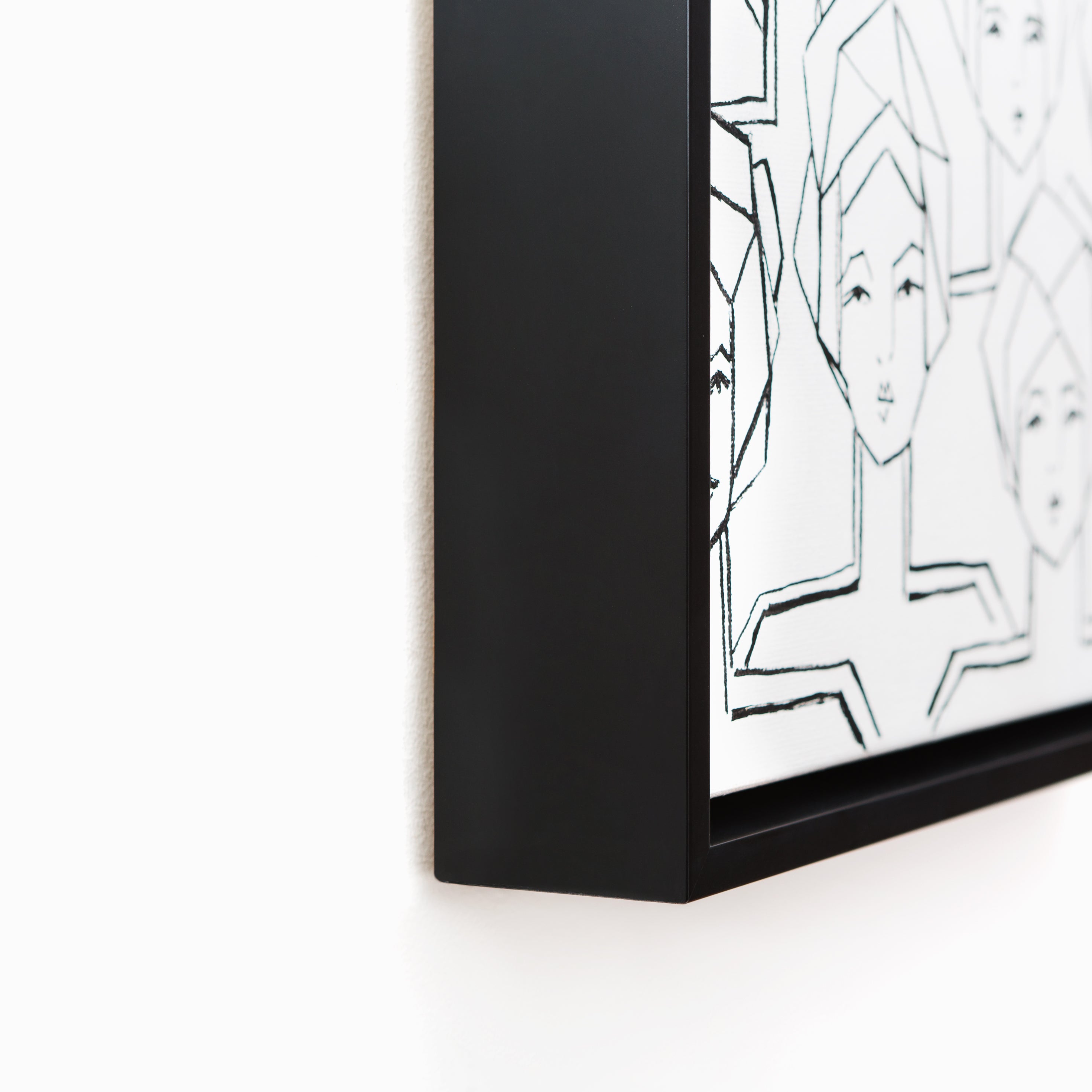 bottom left corner of black and white line painting of women on canvas framed in Heathrow black canvas floater frame