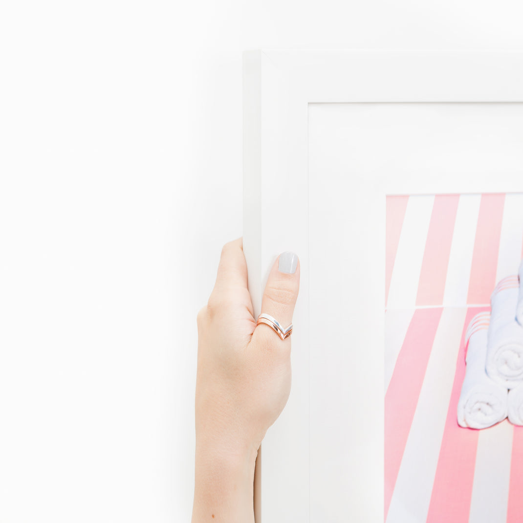top left corner of Photo of towels on a pink striped beach chair framed in modern white Irvine frame with a white mat