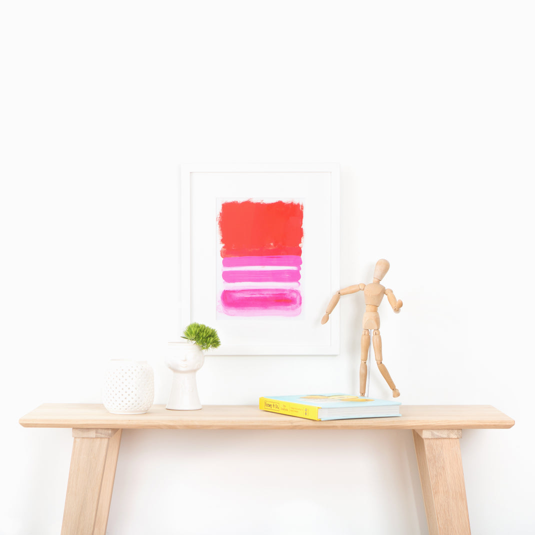 pink and red abstract art print framed in Irvine Slim thin white gallery frame with a white mat hanging on a white wall above a wood console table