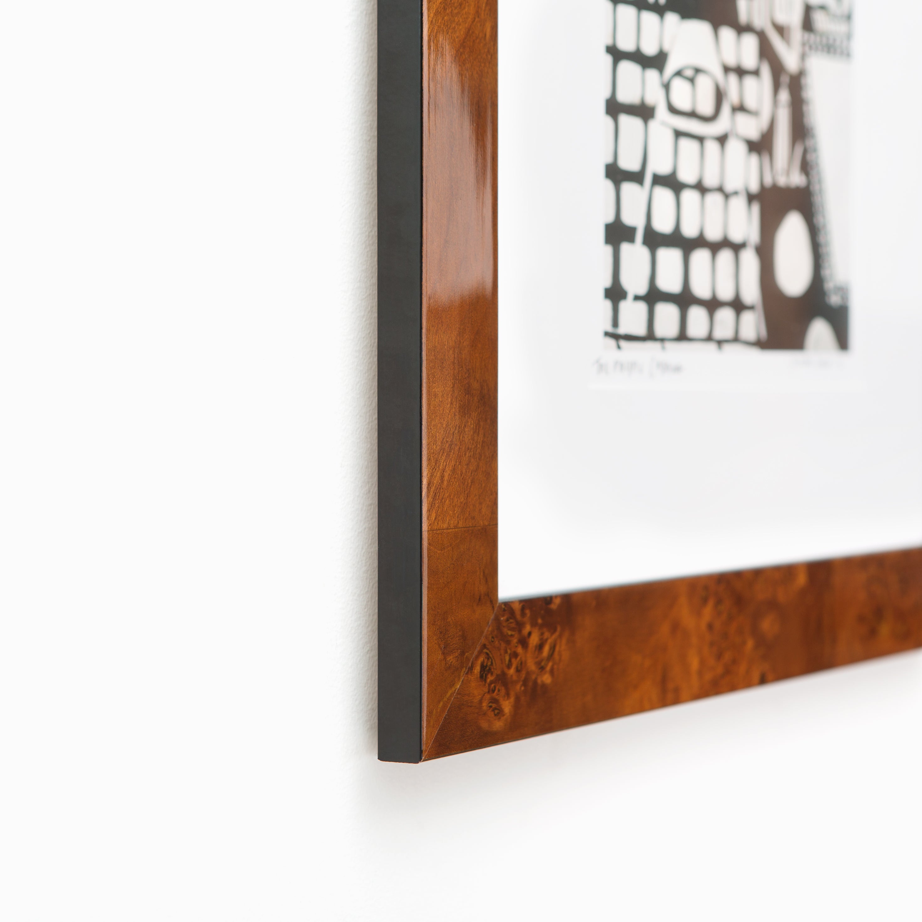 bottom left corner of black and white linocut print framed in Jambi tiger wood frame with white mat
