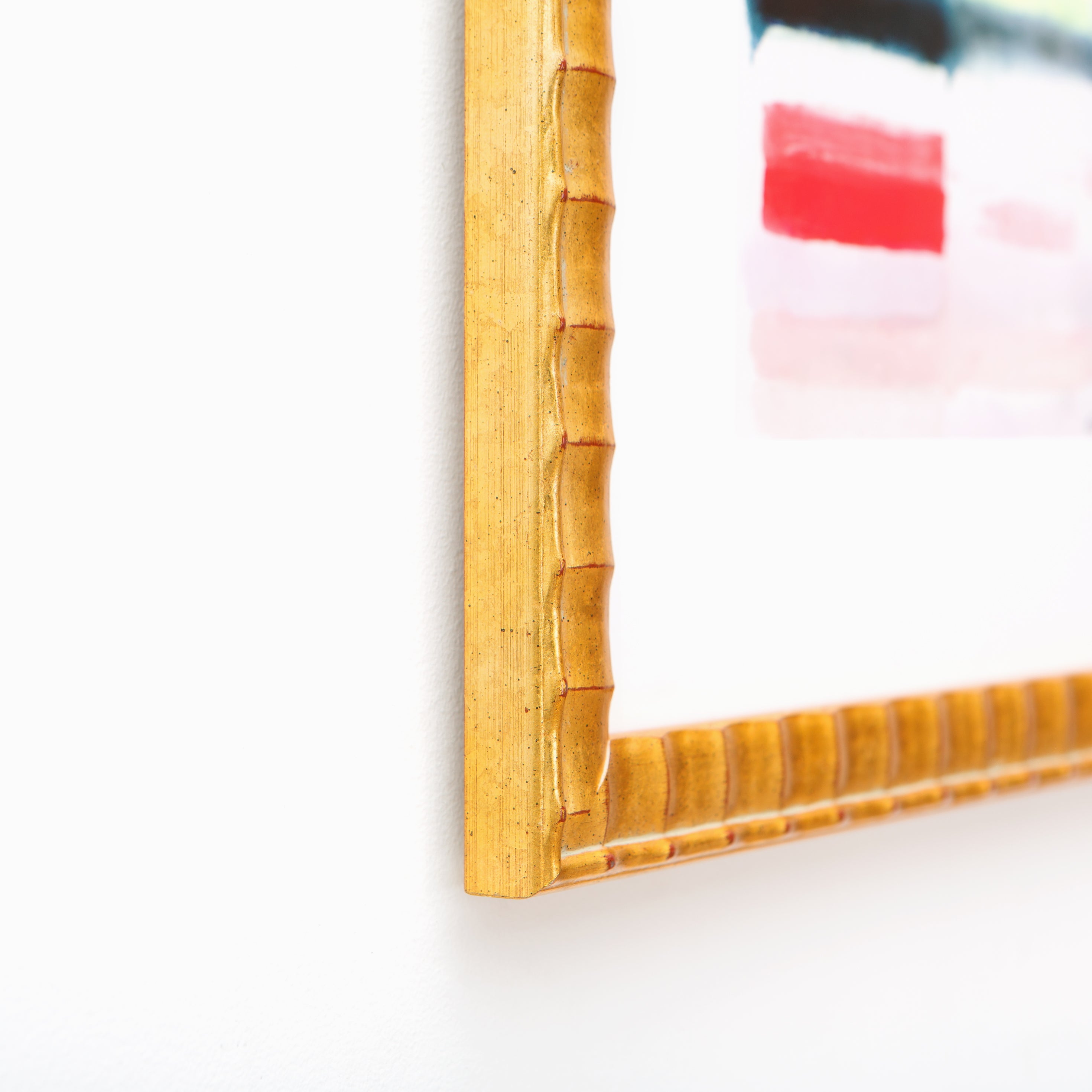 bottom left corner of abstract art framed in rippled gold Lafayette frame with a white mat