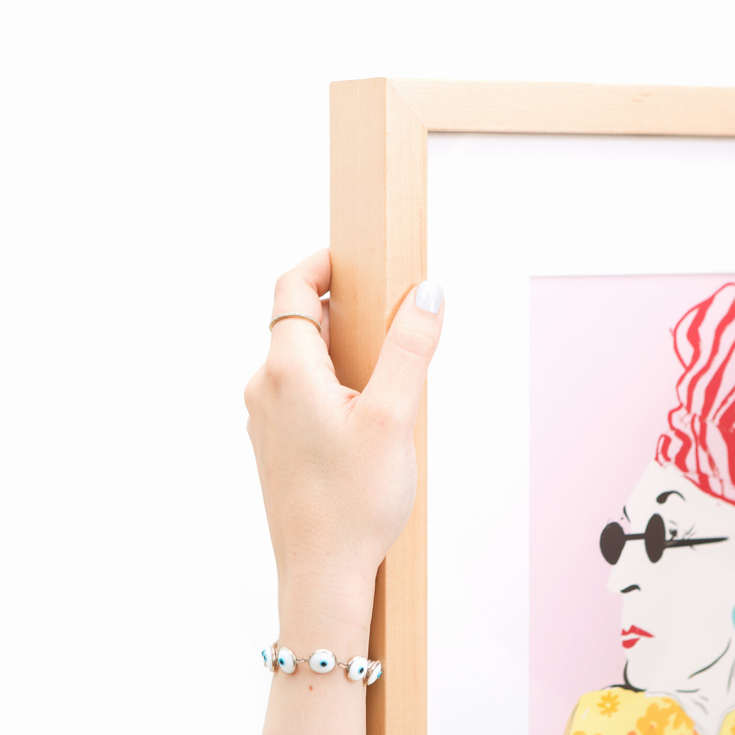 top left corner of illustrated portrait of a woman in a floral dress framed in light wood Marin frame