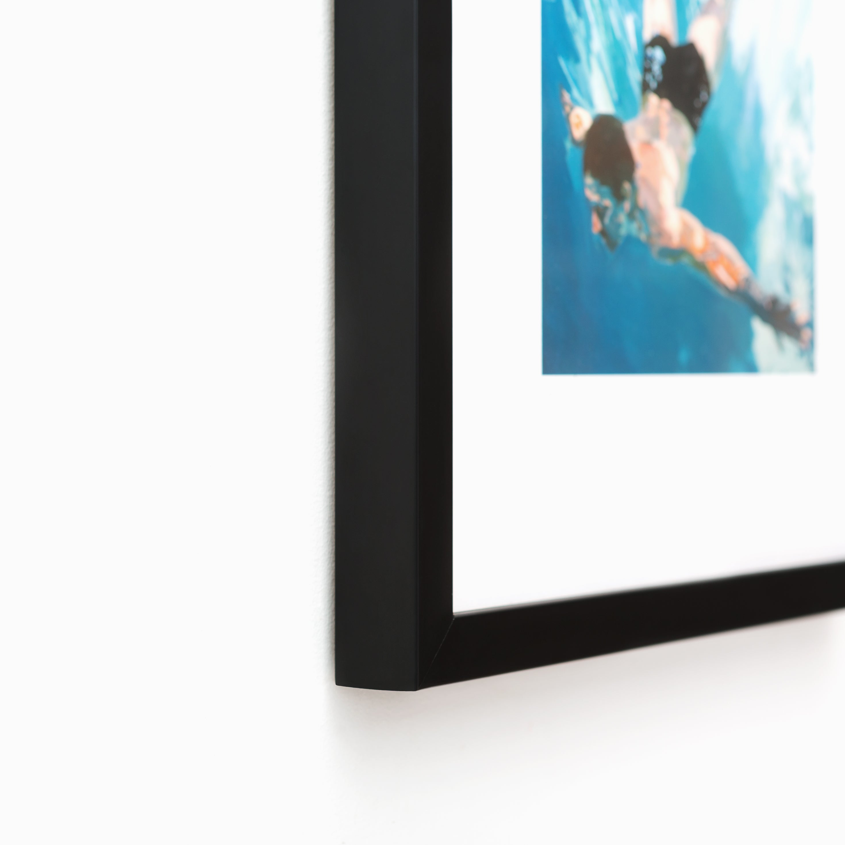 bottom left corner of art print of a man swimming in a pool framed in thin black gallery Mercer Slim frame with a white mat