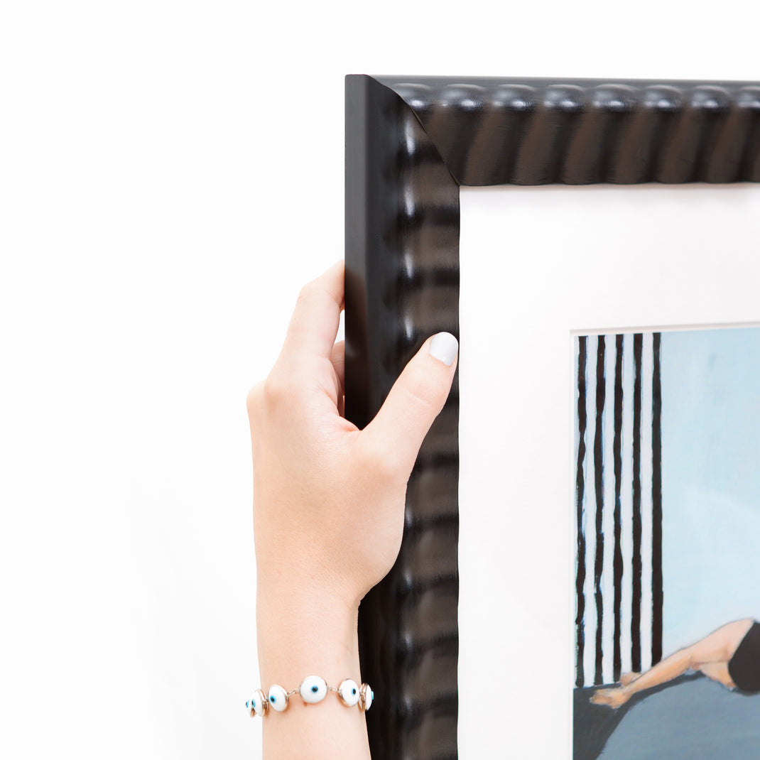 top left corner of abstract photo of a woman lounging in a black bathing suit framed in rippled Rialto frame with a white mat