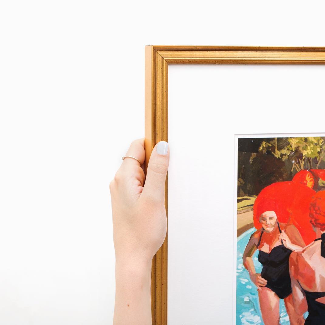 top left corner of art print of women by a pool in vintage bathing suits framed in Richmond gold frame with a white mat