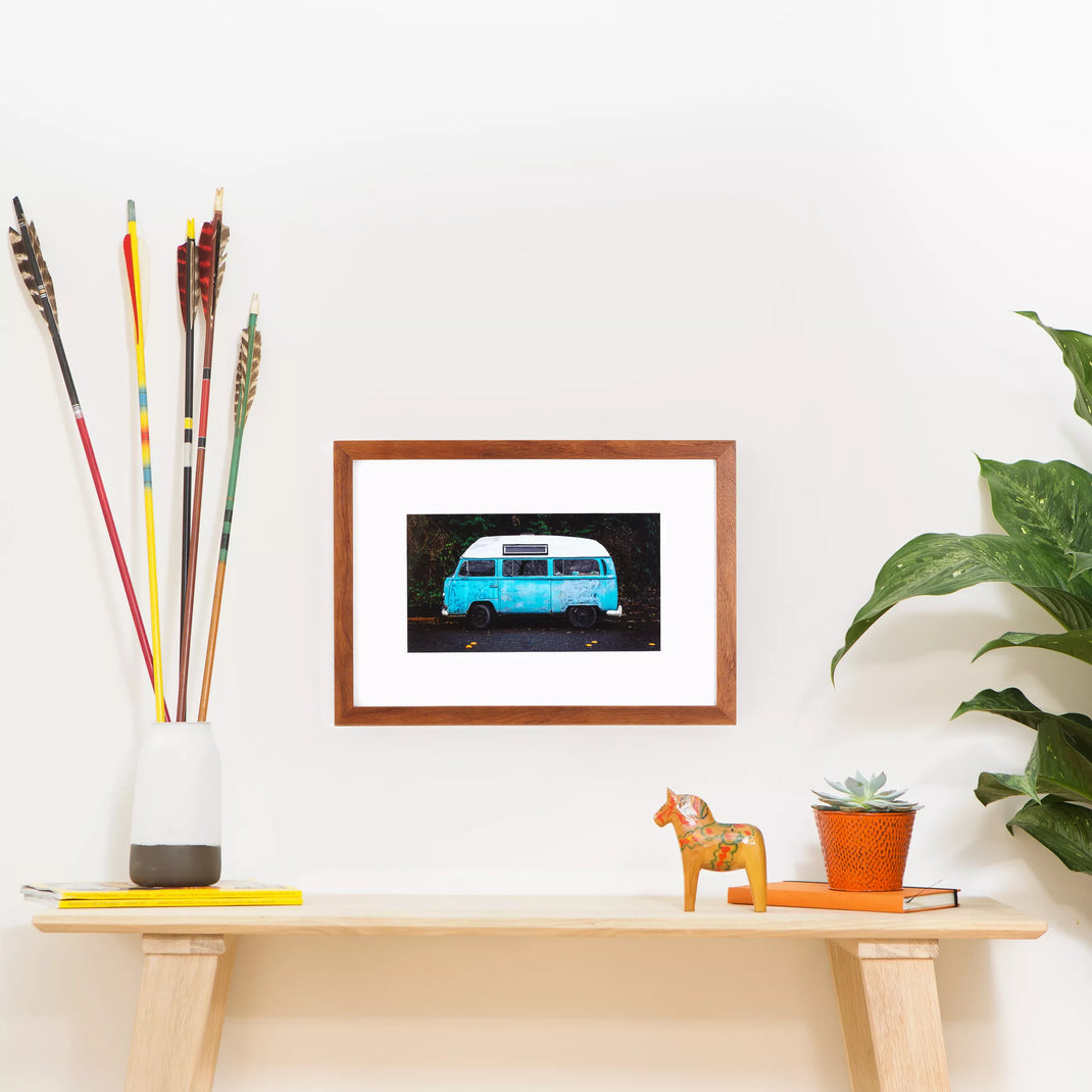 photo of a vintage vw bus framed in warm natural wood Sonoma frame hanging on a white wall above a wood console table